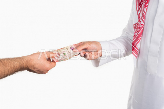 Portrait of a Saudi Arabian Gulf man receiving a sum of money from the hand of another person, paper currency for the Saudi riyal, the concept of business financing, saving and saving money, paper money