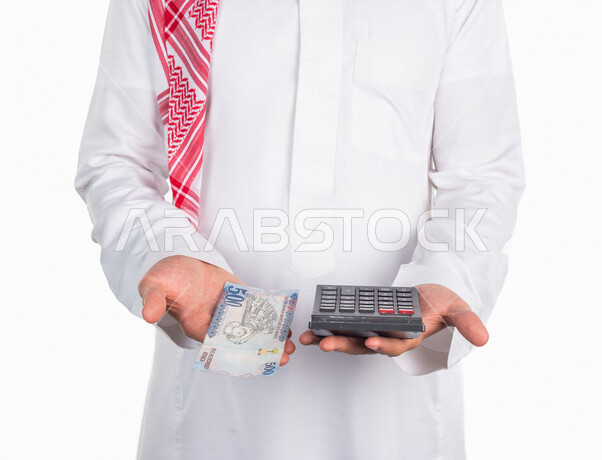 بورتريه لرجل عربي خليجي سعودي، يحمل في يده عملة ورقية من فئة خمسمائة ريال والة حاسبة في اليد الاخرى، العملات الورقية، استخدام الالة الحاسبة لاجراء العمليات الحسابية، ادارة الحسابات