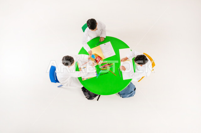 تعزيز المواهب الابداعية عند الطلاب، أنشطة ترفيهية مسلية، تبادل الوجبات الخفيفة في وقت الاستراحة، تعلم مهارات التركيز والابتكار، مفهوم الاهتمام بالهوايات، بورتريه علوي عامودي لتلاميذ عرب خليجيين سعوديين يرتدون الزي التقليدي يقومون بالرسم والتلوين، خلفية بيضاء