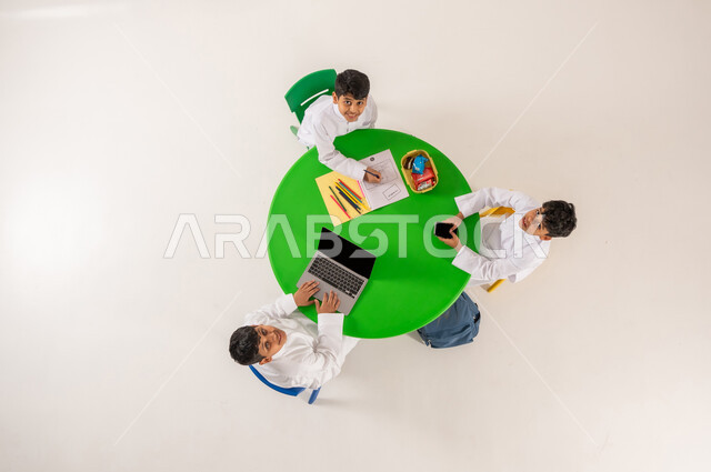 Entertaining activities, concept of interest in hobbies, enhancing creative talents in students, learning concentration and innovation skills, vertical top portrait of Saudi Arabian Gulf students wearing traditional dress drawing, coloring and using modern technical devices, white background