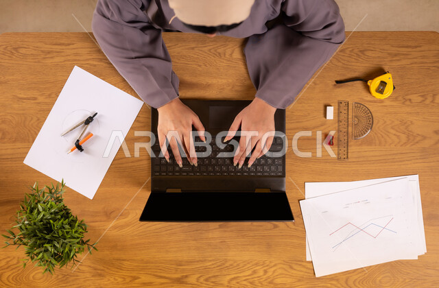 تعلم الحساب والرياضيات من خلال المواقع الالكترونية، التدريب الحسابي عن طريق برامج الاونلاين، دمج التكنولوجيا في الحياة العلمية، استخدام التقنيات الحديثة والمتطورة، صورة علوية عامودية لإمرأة عربية خليجية سعودية تستخدم جهاز الحاسوب المحمول، رسم المخططات البيانية