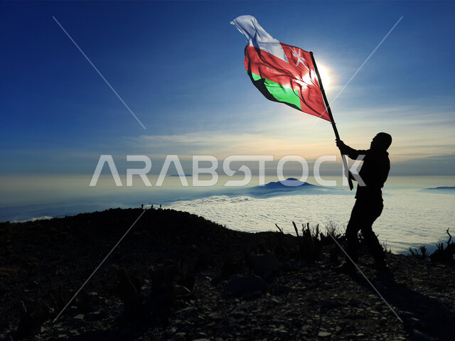 رفع علم الكويت عاليا، مناسبات وأعياد وطنية، الاحتفال بالعيد الوطني الكويتي 25 فبراير، صورة ظلية من الخلف لرجل يرفع الراية وقت غروب الشمس، إحياء ذكرى يوم العلم، حب الوطن والإنتماء اليه، الفخر والإعتزاز بالرموز والثقافة الكويتية