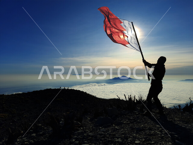 رفع علم الكويت عاليا، مناسبات وأعياد وطنية، الاحتفال بالعيد الوطني الكويتي 25 فبراير، صورة ظلية من الخلف لرجل يرفع الراية وقت غروب الشمس، إحياء ذكرى يوم العلم، حب الوطن والإنتماء اليه، الفخر والإعتزاز بالرموز والثقافة الكويتية