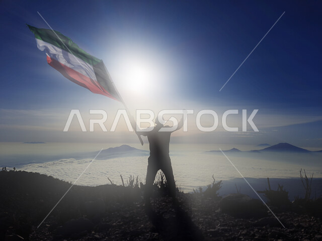 رفع علم الكويت عاليا، مناسبات وأعياد وطنية، الاحتفال بالعيد الوطني الكويتي 25 فبراير، صورة ظلية من الخلف لرجل يرفع الراية وقت غروب الشمس، إحياء ذكرى يوم العلم، حب الوطن والإنتماء اليه، الفخر والإعتزاز بالرموز والثقافة الكويتية