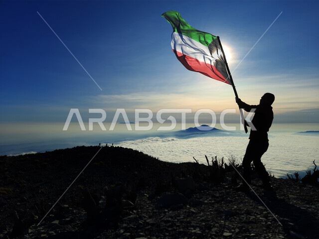 رفع علم الكويت عاليا، مناسبات وأعياد وطنية، الاحتفال بالعيد الوطني الكويتي 25 فبراير، صورة ظلية من الخلف لرجل يرفع الراية وقت غروب الشمس، إحياء ذكرى يوم العلم، حب الوطن والإنتماء اليه، الفخر والإعتزاز بالرموز والثقافة الكويتية