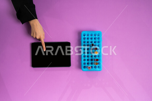 إجراء تجارب وبحوث علمية عبر التكنولوجيا الحيوية، البحث والتطوير العلمي في مجال الكيمياء، عرض شاشة سوداء فارغة، بورتريه علوي عامودي ليد إمرأة عربية سعودية خليجية تمسك جهاز الآيباد وبجانبها أنابيب الاختبار، تدوين نتائج التحاليل المخبرية على التابليت، خلفية وردية