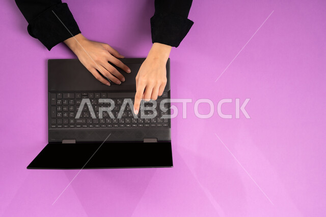 عرض شاشة سوداء فارغة، مهن ووظائف مكتبية سعودية، دمج العمل مع التقنية والتكنولوجيا الحديثة، مفهوم ادارة الاعمال وتحقيق الأهداف أونلاين، إنجاز المهام المطلوبة عن بعد، بورتريه علوي عامودي ليدين إمرأة عربية خليجية سعودية تعمل على جهاز الحاسب المحمول، خلفية وردية