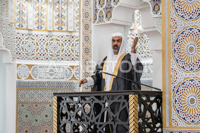 توجيه الناس نحو الحق والهداية, مفهوم العبادة والتقرب إلى الله تعالى, دور أئمة المساجد والخطباء في نشر الدين، إمام عربي خليجي إماراتي يرتدي البشت والكندورة والغترة البيضاء يقف أمام مكبر الصوت ويلقي الخطبة على المنبر, نداء المسلمين لأداء الفرائض