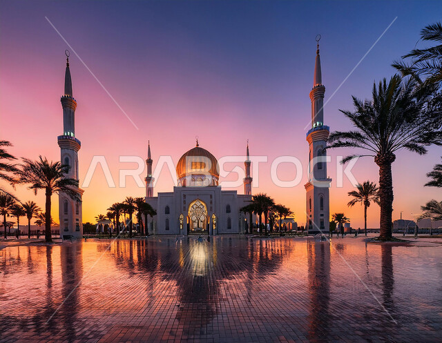 منظر مسجد كبير وقت غروب الشمس، مفهوم العبادة والتقرب إلى الله، الفن الهندسي المعماري للمآذن والقبب المزخرفة على الطراز الحديث، أماكن ومعالم دينية مقدسة في المملكة العربية السعودية، دعوة ونداء المسلمين إلى الصلاه، الاهتمام في زراعة أشجار النخيل في ساحة الجامع