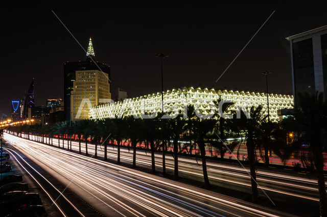 مكتبة الملك فهد الوطنية المضاءة في مدينة الرياض في الليل، مركز ثقافي للتشجيع على تنمية الثقافة والقراءة، الفن الهندسي المعماري المميز لمباني المملكة العربية السعودية، معالم ثقافية سياحية مشهورة، الاهتمام بالتشجير وزراعة اشجار النخيل في الشوارع العامة