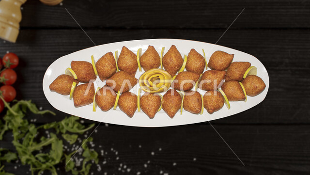 طبق مزين من الكبة المقلية ذات الون الذهبي, وجبة ذات قيمة غذائية عالية، فنون التقديم في مطاعم ومطابخ المملكة العربية السعودية، أطباق من المأكولات العربية التقليدية الشعبية، وصفات طعام شهية صحية ولذيذة