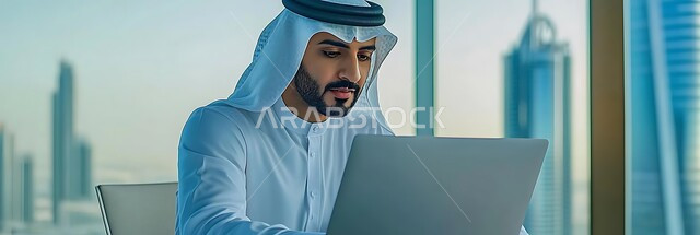 استخدام الأجهزة التقنية الحديثة في الأعمال المكتبية, إنجاز مهام العمل, صورة مقربة لرجل عربي خليجي سعودي يرتدي الثوب التقليدي والغترة يجلس داخل المكتب ويعمل على جهاز الحاسوب المحمول
