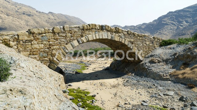 Old stone bridge built over a dry riverbed in the mountains of Saudi Arabia, historical architecture of ancient monuments, remote areas and abandoned villages, distinctive landscapes, stone formations and formations, ancient architectural art