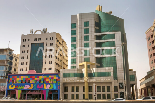 العمل على تنمية المباني الهندسية الحديثة, الفنون والتصاميم المعمارية المتطورة لشوارع مدينة الرياض, الأبراج وناطحات السحاب في السعودية, النهضة الاقتصادية في المملكة, المنشآت السكنية والتجارية جانب محل العاب الحسن على طريق الملك فهد في وقت النهار