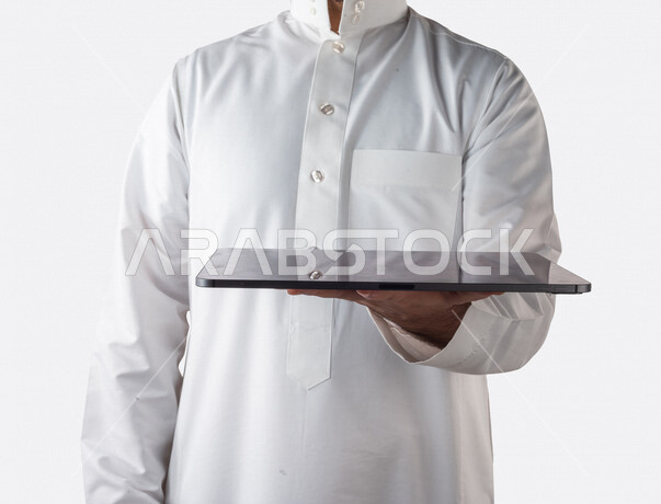 بورتريه لرجل خليجي سعودي يحمل بيده جهاز التابلت ، استخدام اجهزة تقنية حديثة ، خلفية بيضاء