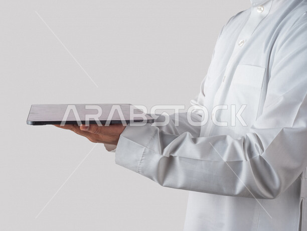 بورتريه لرجل خليجي سعودي يحمل بيده جهاز التابلت ، استخدام اجهزة تقنية حديثة ، خلفية بيضاء