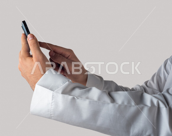 Portrait of a Saudi Gulf man holding a mobile phone, clicking on the screen, using the touch feature, using modern technical devices, white background