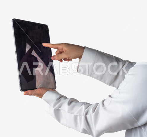 بورتريه لرجل خليجي سعودي يحمل بيده جهاز التابلت ، ينقر باصبعه على شاشة الجهاز التقني ، استخدام خاصية اللمس، استخدام اجهزة تقنية حديثة ، خلفية بيضاء
