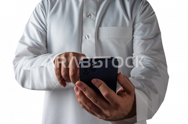 بورتريه لرجل خليجي سعودي يحمل بيده الهاتف المحمول النقر بالاصبع على الشاشة ،استخدام خاصية اللمس، استخدام اجهزة تقنية حديثة ،  خلفية بيضاء