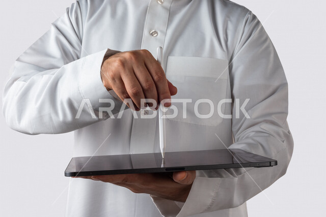 بورتريه لرجل خليجي سعودي يحمل بيده جهاز التابلت ، يستخدم القلم الخاص للضغط على شاشة الجهاز التقني ،تنظيم وادارة الاعمال عبر الجهاز التقني ، خلفية بيضاء