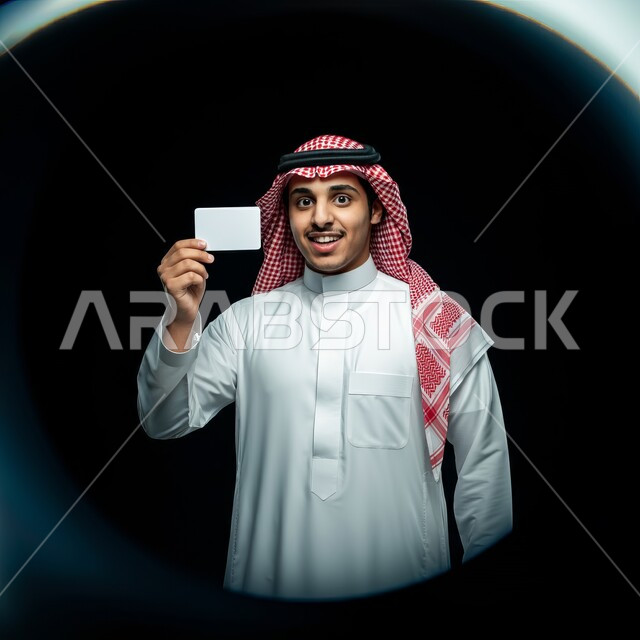 لوح اعلاني فارغ، موك اب مستطيل أبيض، اعلانات و عروضات تسويقية, النظر الى الكاميرا بايماءات السرور السعادة، بورتريه لرجل عربي خليجي سعودي يرتدي الشماغ والثوب التقليدي يحمل بيده لوحة بيضاء مستطيلة، خلفية سوداء