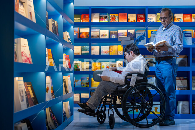 قضاء وقت الفراغ بالتعلم والثقافة، مفهوم محو الامية، هواية حب المطالعة والاستكشاف, صورة لرجل كبير السن مقعد عربي خليجي سعودي يرتدي الثوب التقليدي والشماغ يجلس على الكرسي يحمل بيده كتاب علمي تثقيفي في معرض الكتاب