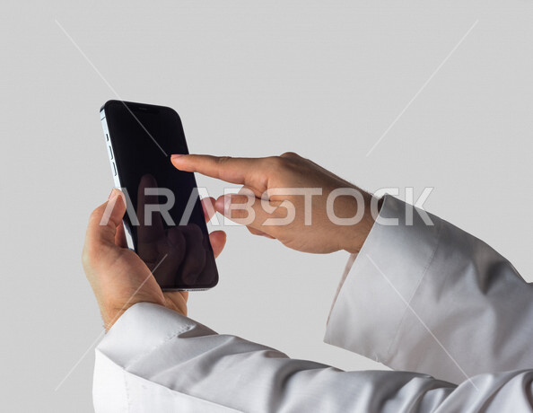 Portrait of a Saudi Gulf man holding a mobile phone, clicking on the screen, using the touch feature, using modern technical devices, white background