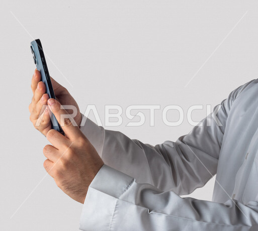بورتريه لرجل خليجي سعودي يحمل بيده الهاتف المحمول ، اجراء اتصال فيديو ،تصوير سيلفي ،استخدام اجهزة تقنية حديثة ،  خلفية بيضاء