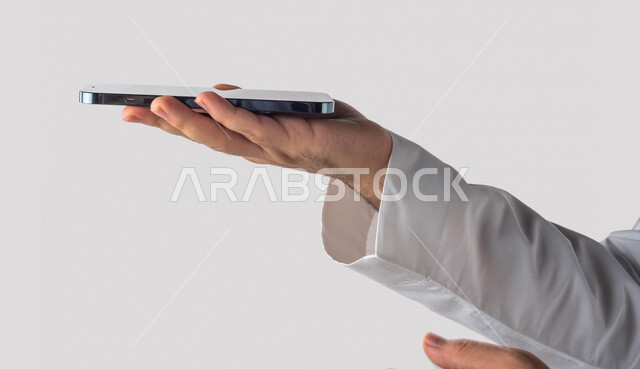 بورتريه لرجل خليجي سعودي يحمل بيده الهاتف المحمول ، استخدام اجهزة تقنية حديثة ،  خلفية بيضاء