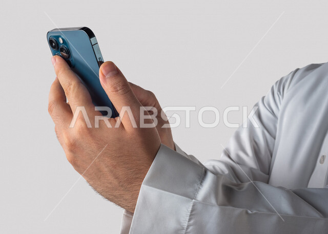 بورتريه لرجل خليجي سعودي يحمل بيده الهاتف المحمول ، اجراء اتصال فيديو ،تصوير سيلفي ،استخدام اجهزة تقنية حديثة ،  خلفية بيضاء
