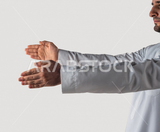 بورتريه لرجل خليجي سعودي يقوم بايماءات يد مختلفة ، يحمل شيء بين يديه، رفع و حمل شيء ما، اشارة الامساك، خلفية بيضاء