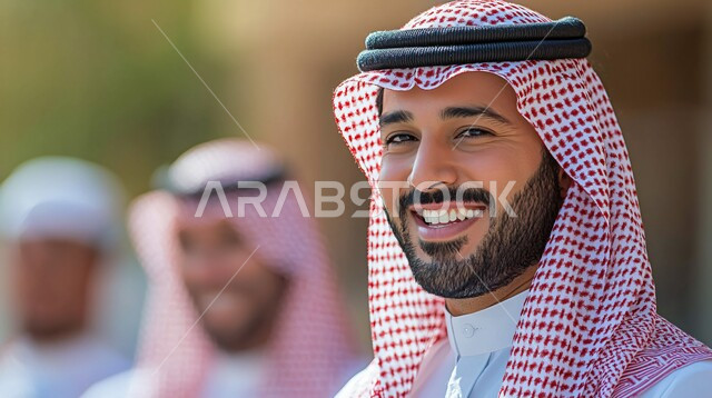  الاناقة والاهتمام بالمظهر الخارجي, صورة مقربة لرجل عربي خليجي سعودي مبتسم يرتدي الثوب التقليدي والشماغ ينظر الى الكاميرا بايماءات الثقة بالفس والسرور