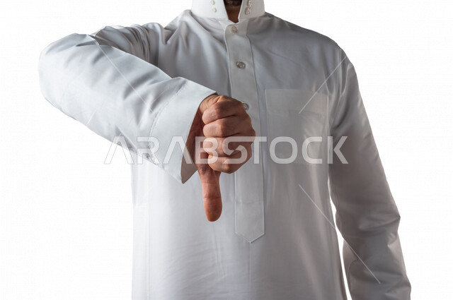 بورتريه لرجل خليجي سعودي يرتدي الزي الخليجي التقليدي يقوم بايماءات يد مختلفة ، يخفض اصبع الابهام لعدم اعجابه بشيء ما ، خلفية بيضاء
