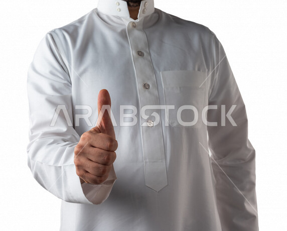بورتريه لرجل خليجي سعودي يرتدي الزي الخليجي التقليدي يقوم بايماءات يد مختلفة ، يرفع اصبع الابهام لاعلى لاعجابه بشيء ما ، خلفية بيضاء