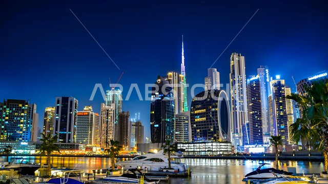 Urban growth and development on the Gulf coast, modern architectural style of towers and skyscrapers in Dubai, famous landmarks and tourist places, residential and commercial buildings and facilities illuminated at night in the United Arab Emirates, attracting and attracting tourists from all over the world