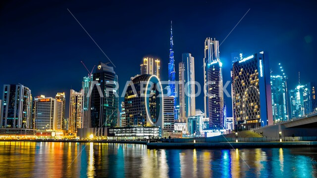 Modern architectural style of towers and skyscrapers in Dubai, famous landmarks and tourist places, residential and commercial buildings and facilities illuminated at night in the United Arab Emirates, attracting and attracting tourists from all over the world, urban growth and development on the Gulf coast