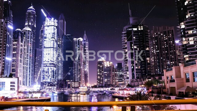 Skyscrapers and tall towers illuminated at night, famous landmarks and tourist places, residential and commercial buildings and facilities in the United Arab Emirates, attracting and attracting tourists from all over the world, urban growth and development on the Gulf coast