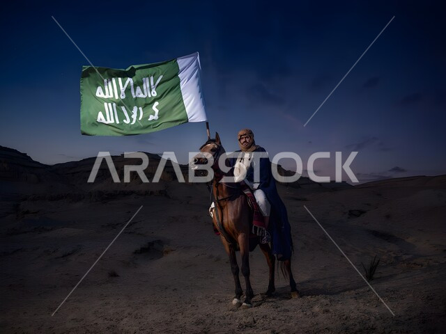 التباهي والفخر في الهوية الوطنية، شاب عربي خليجي سعودي يرتدي الزي التقليدي والشماغ ويمتطي حصان عربي أصيل في وقت الليل، رفع علم السعودية إحتفالا بذكرى اليوم الوطني السعودي، يوم العلم السعودي 11 مارس، أنشطة وفعاليات ركوب الخيل في الصحراء