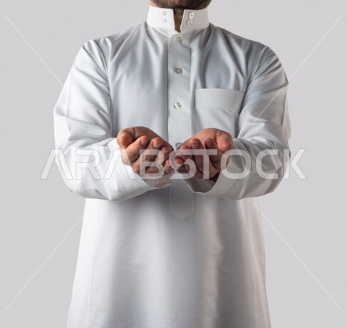 بورتريه لرجل خليجي سعودي يقوم بايماءات يد مختلفة، يفتح يديه لعرض شيء ما، يحمل شيء بين يديه، رفع و حمل شيء ما، اشاره الامساك، خلفية بيضاء