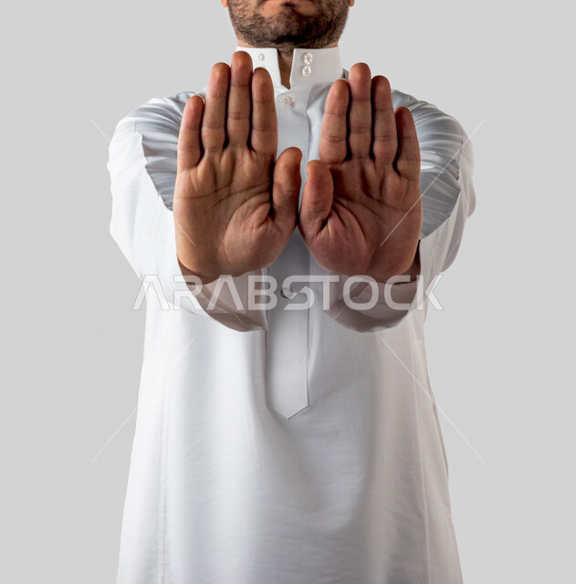 بورتريه لرجل خليجي سعودي يقوم بايماءات يد مختلفة ، ايماءة يده تدل على المنع والتوقف عن فعل شيء ، خلفية بيضاء