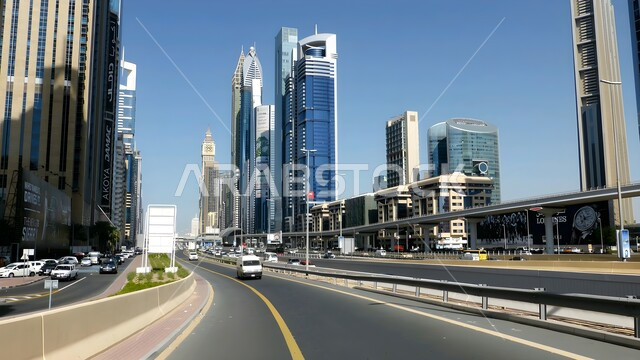 Traffic in streets and roads, growth and urban engineering progress in the modern style of buildings and skyscrapers in the city of Dubai, interest in infrastructure development, famous landmarks and tourist places in the United Arab Emirates