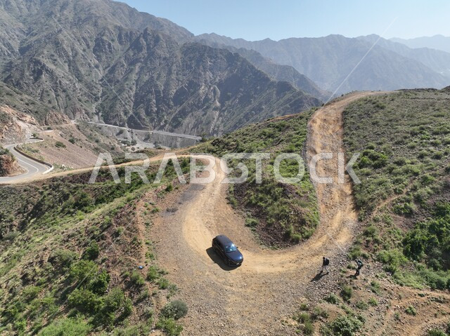 Rock formations and structures in Jazan city, green trees and plants planted on Al-Qahr Mountains, natural scenery in tourist places in the Kingdom of Saudi Arabia, a car driving on a mountain road amidst the ranges and heights