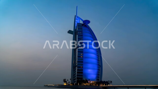 الفن الهندسي المعماري لفندق برج العرب المضاء باللون الأزرق في مدينة دبي, مناطق جذب واستقطاب السياح من شتى أنحاء العالم، النمو و التطور العمراني للابراج وناطحات السحاب على ساحل الخليج العربي، أماكن ومعالم سياحية مشهورة في الإمارات العربية المتحدة