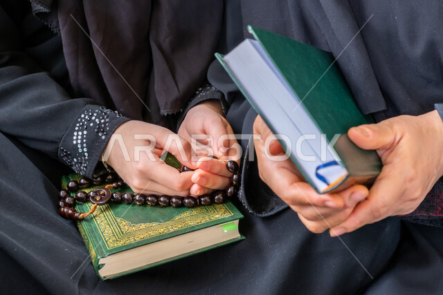 مفهوم العبادة والتقرب من الله تعالى، فضل وثواب قراءة وحفظ القرآن الكريم, صورة مقربة لإمرأتان عربيتان خليجيتان سعوديتان ترتديان العباءة السوداء وتحملان المصحف الشريف والسبحة، أجواء دينية روحانية، الاجتهاد في الطاعات والأدعية والأذكار