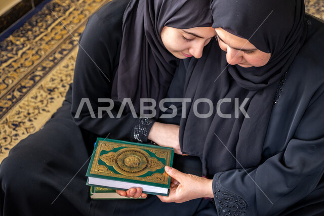 العبادة والتقرب إلى الله تعالى, أجواء روحانية دينية, فتاة عربية خليجية سعودية ترتدي العباءة السوداء تقوم بمعانقة والدتها, قراءة وتلاوة القرآن الكريم, التعبد في أحد بيوت الله, تربية البنات على تعاليم الدين الصحيح