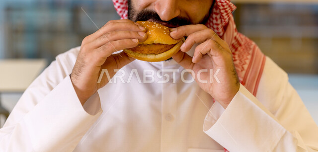 أضرار تناول المأكولات السريعة ، رجل عربي سعودي خليجي يقضي اجواء رائعة  في المطعم ، وجبات سريعة ، تناول الطعام في ردهة المطاعم في المركز التجاري .