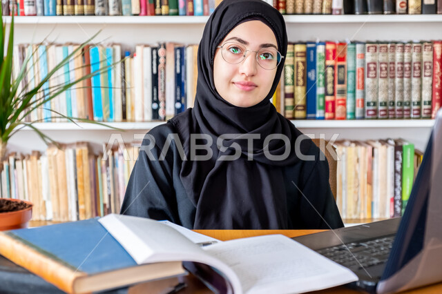 استخدام الأجهزة التقنية الحديثة لمتابعة المحاضرات الجامعية، التعليم عن بعد، المناهج و المواد التعليمية في السعودية، مفهوم الثقافة والتعلم الذاتي , صورة مقربة لشابة عربية خليجية سعودية محجبة مبتسمة ترتدي عباءة سوداء تنظر الى الكاميرا بايماءات السعادة