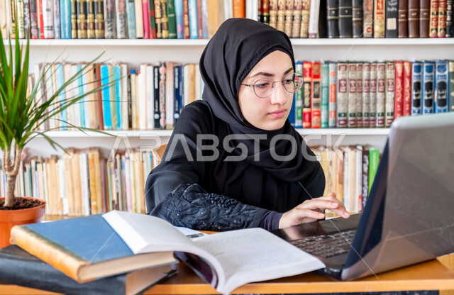 التعليم عن بعد عن طريق الانترنت، المناهج والمواد التعليمية في السعودية، مفهوم الثقافة والتعلم الذاتي , صورة مقربة لشابة عربية خليجية سعودية محجبة ترتدي عباءة سوداء تقوم بمتابعة الدراسة عبر الحاسب، استخدام الأجهزة التقنية الحديثة لحضور المحاضرات الجامعية