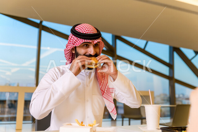 صورة لمائدة طعام خاصة برجل سعودي خليجي ، يقضي اجواء رائعة  في المطعم ، وجبات سريعة ، تناول الطعام في ردهة المطاعم في المركز التجاري .