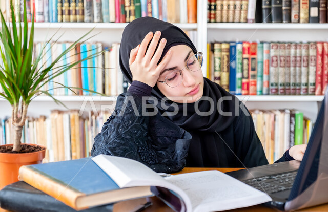 دمج التقنيات الحديثة بالتعليم الأكاديمي, المناهج والمواد التعليمية في الكليات السعودية, مفهوم الاجتهاد والتفوق، شابة عربية خليجية سعودية تضع يدها على رأسها بإيماءات التعب والإرهاق، المحاضرات الجامعية الإلكترونية عن بعد، مراجعة الدروس اليومية عبر الحاسب المحمول